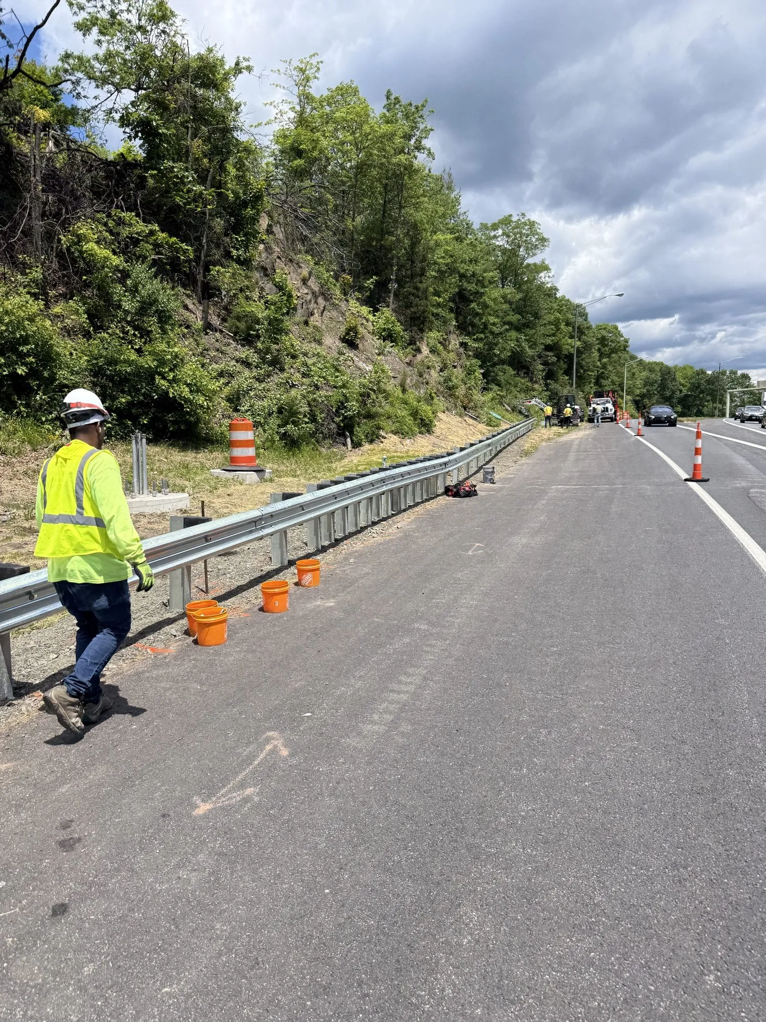 Completed galvanized highway guardrail run with a Cristiano & Son worker walking the line