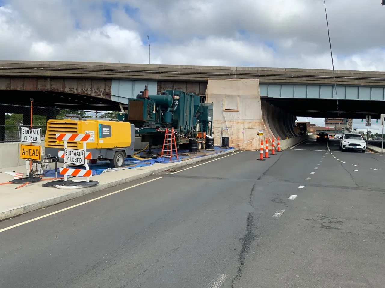 Lead-hazard containment enclosure built beneath a highway underpass for bridge coating removal