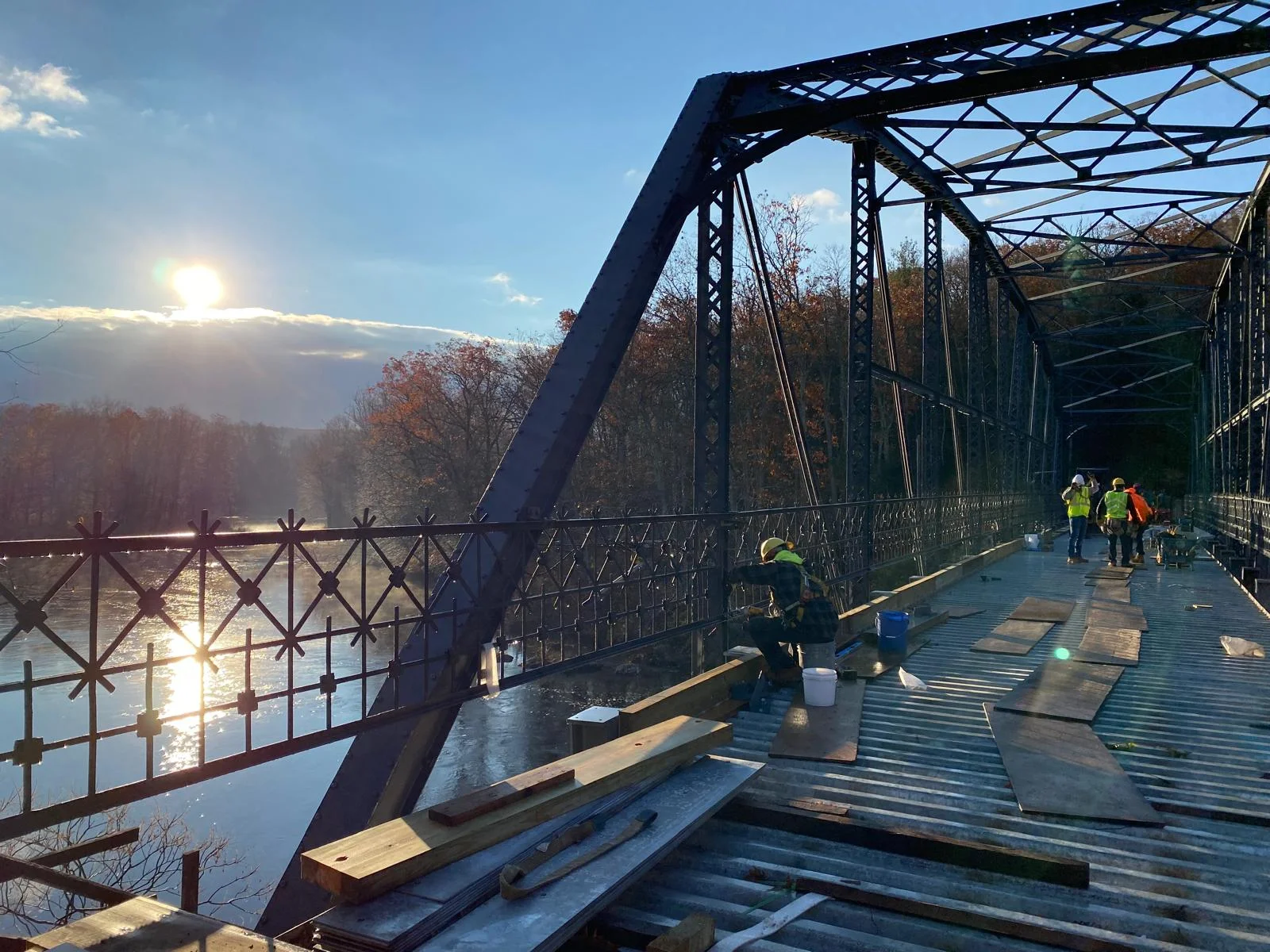 Cristiano & Son crew working on a historic iron truss bridge at sunset