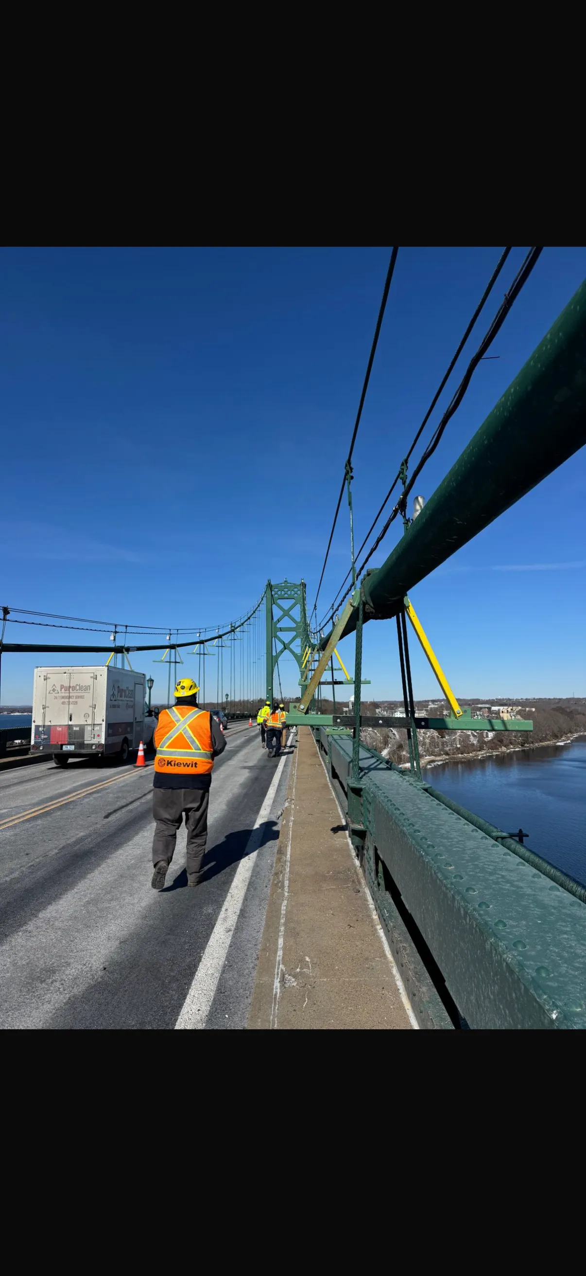 Workers walking the deck of a major suspension bridge